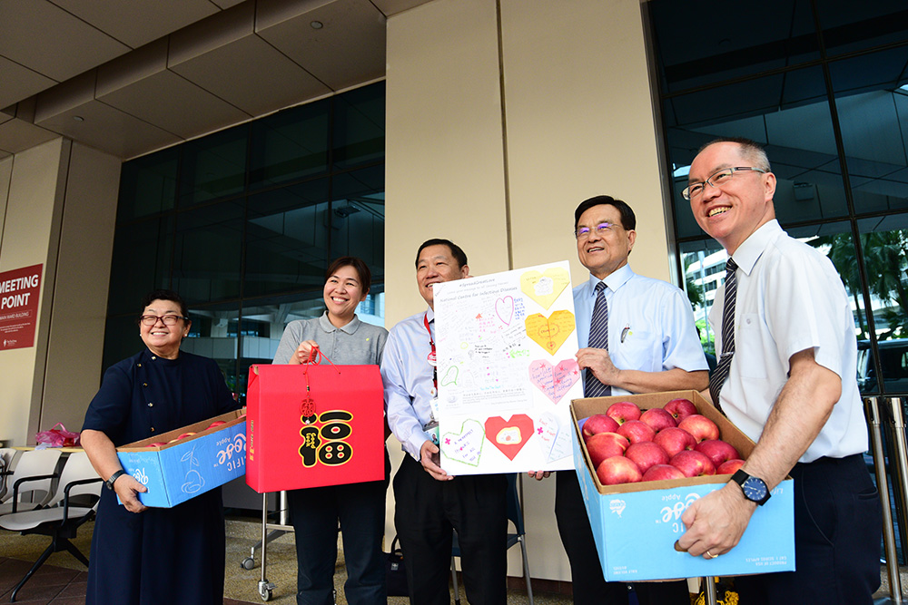 Tzu Chi CEO Mr Low Swee Seh (second from right) and volunteer representatives handing over care packages, fruit baskets and a large greeting card to Associate Professor Chin Jing Jih, the Chairman of the Medical Board of TTSH. (Photo by Wong Twee Hwee)