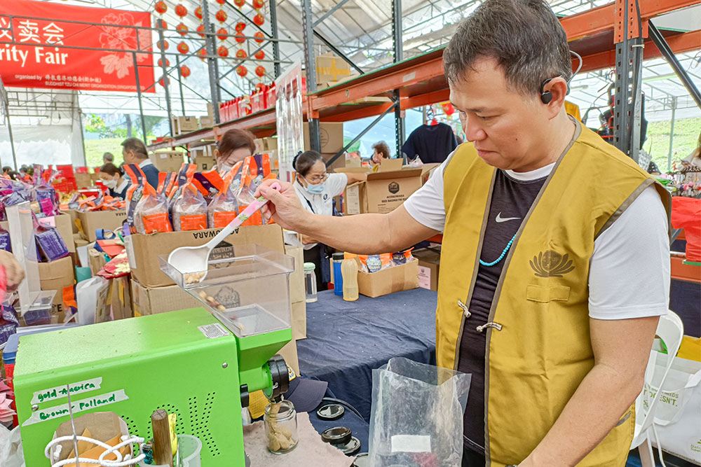 Ronald Neo, the owner of the nut jam stall, demonstrates making cold-pressed organic nut jam while introducing different ways to enjoy the jam. (Photo by Ng Hock Soon)